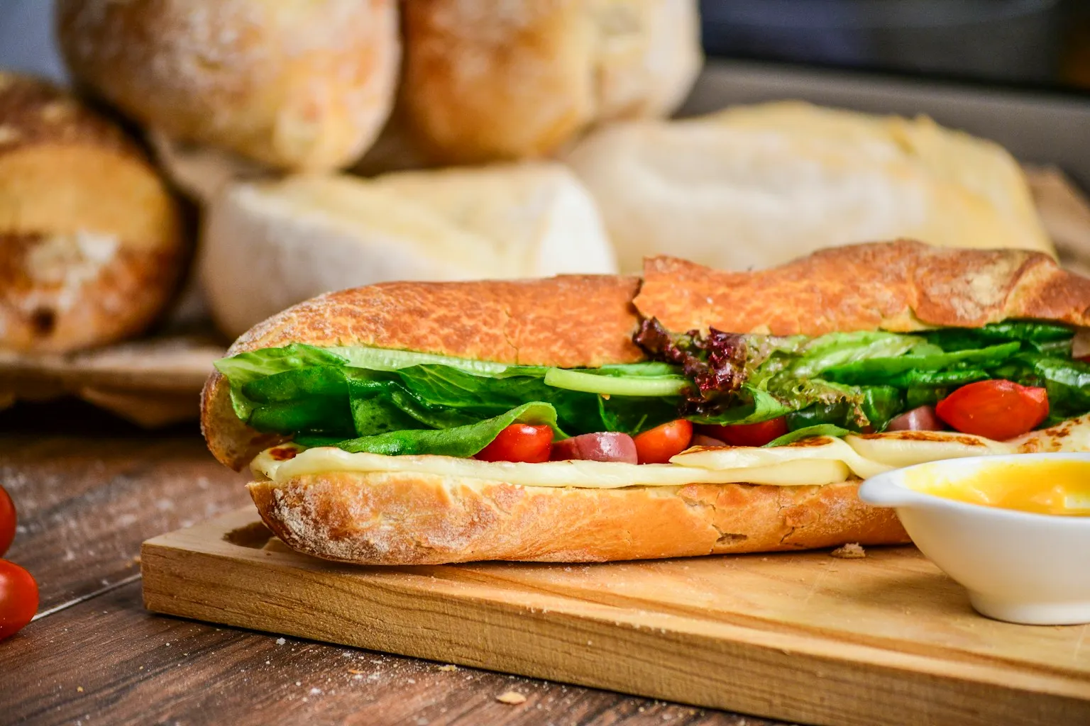 Sandwich sur pain frais, garni de légumes, posé sur une planche